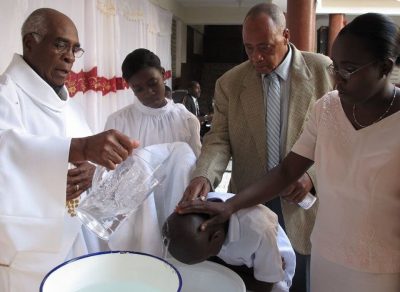 Deacon Rodrigue Mortel (left) baptizes a child in 2010 in his hometown of St. Marc, Haiti. (Paul McMullen/CR Staff)
